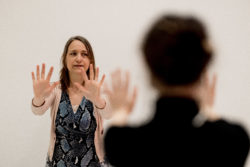 two persons facing each other practising qigong, arms stretched, hands standing, fingers spread