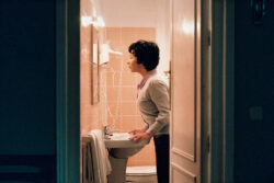 A woman looks at herself in a bathroom mirror