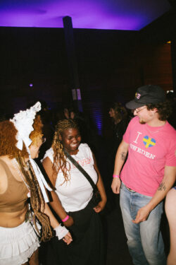 A group of five people gathered around a man, engaged in conversation and smiling at each other.