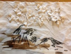 A piece of fabric in beige with little fabric scraps applied to it.