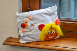 A pillow with colourful embroidery is positioned in a windowsill.