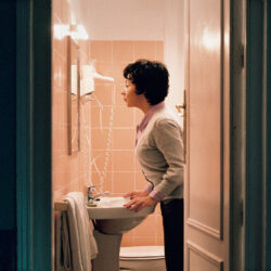 A woman looks at herself in a bathroom mirror