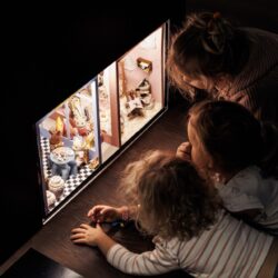 Three children are impressed by a diorama with mouse puppets and their interior.