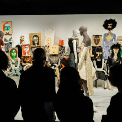 A group of people observes the moving mannequins on Dirk Saene’s catwalk installation