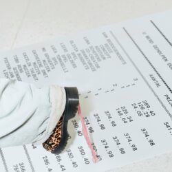A person wearing light jeans and leopard print shoes stands on a large printed receipt with visible itemized prices and text.