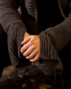Twee handen en oversized mouwen van een bruine gebreide pull