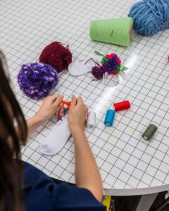 Een kind knutselt een sok met kleurrijke materialen.