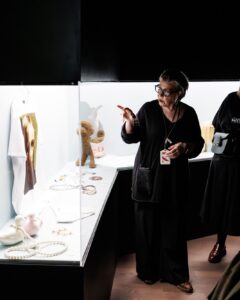 A guide points to a display while others observe the pieces in a museum.