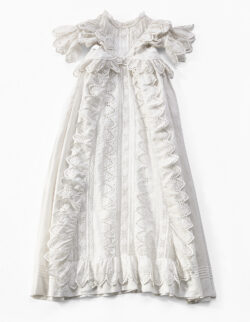 Babyjurk in katoen, 1868-70. Het lijfje en het ingezette stuk van de rok zijn gemaakt uit aan elkaar genaaide stroken geborduurde band en tussenzetsels door een linnennaaister van de Amsterdamse modewinkel À la Ville de Paris. Maison M.J.C. de Meijere.