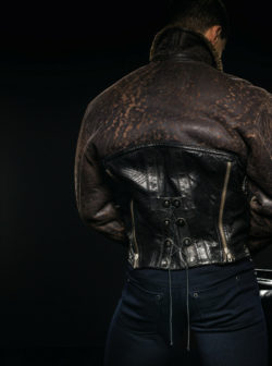 Detail of backside of model in leather vest with blue pants