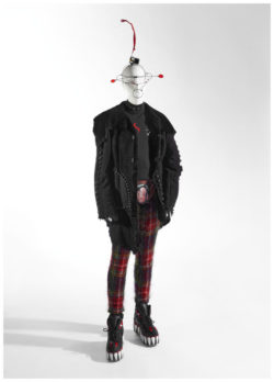 Mannequin with metal headpiece, black coat, red checkered pants and platform shoes