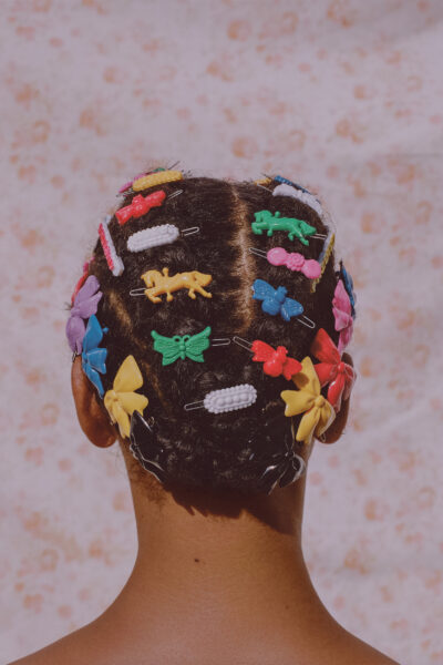 A woman with colourful barrettes adorning her head.