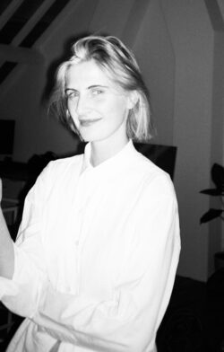 Annaëlle Reudink wears an oversized, white shirt; she has blonde, mid-length hair and smiles