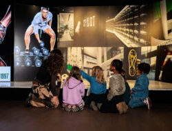 A group of children is looking at various sports items at the Antwerp Six exhibition.